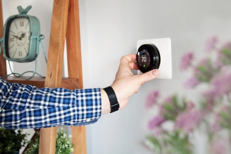 Man is Adjusting a temperature on the thermostat