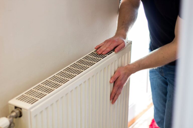 Man is checking radiator is it heating