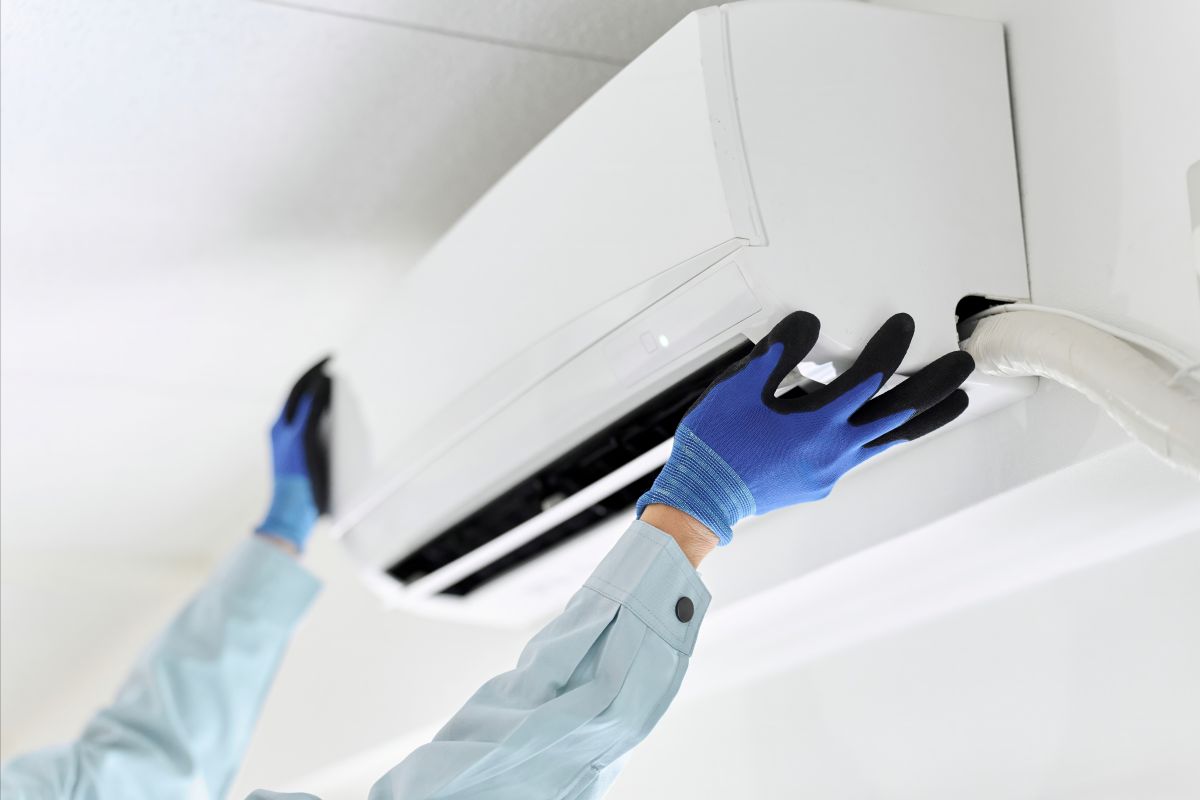 hands installing an AC unit on the wall