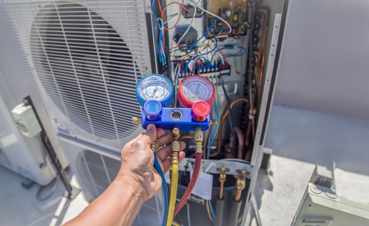Air conditioning, HVAC service technician using gauges to check refrigerant and add refrigerant