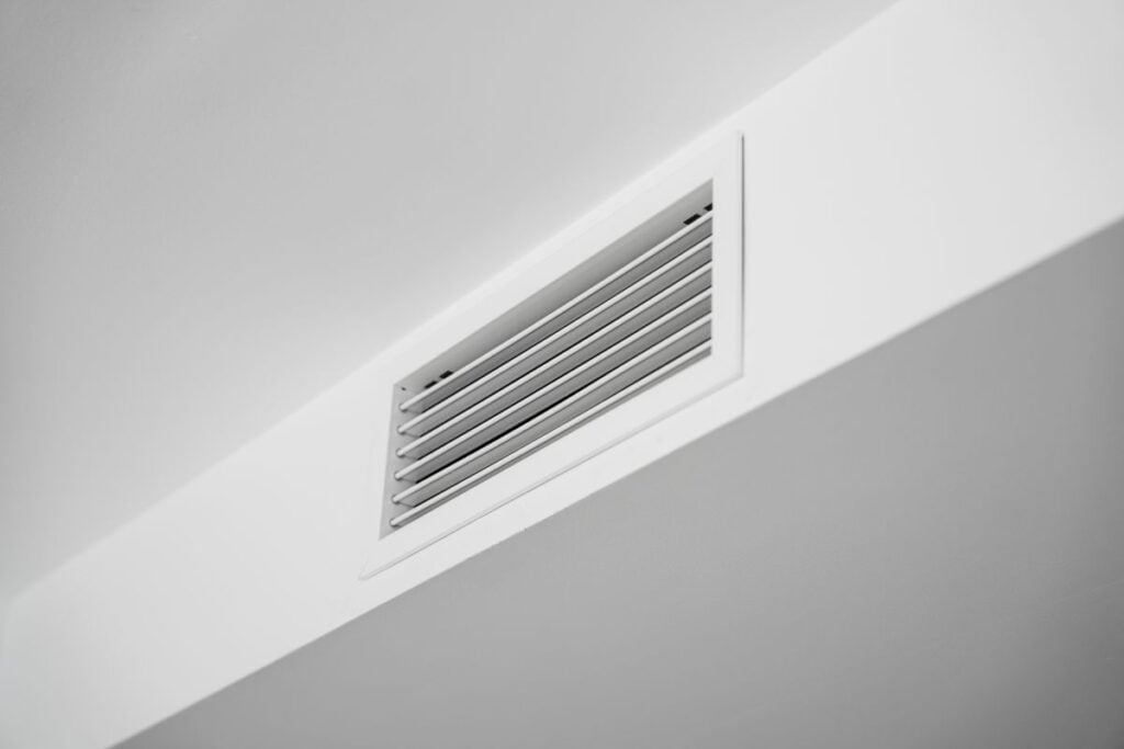 White ceiling air vent grille in modern home interior, clean HVAC ventilation system