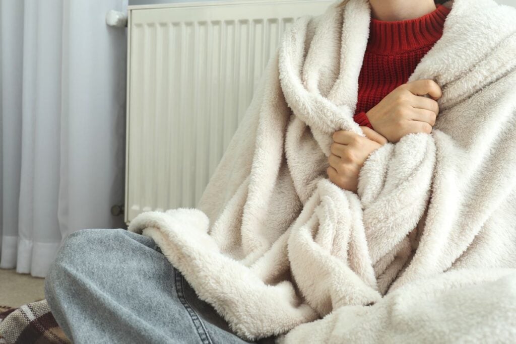 Concept of heating season with girl sitting near radiator
