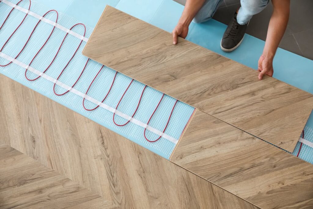Professional contractor installing underfloor trace heating system indoors, closeup